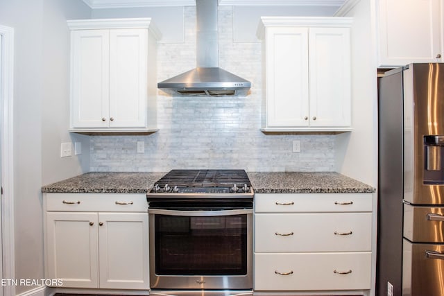 kitchen with backsplash, appliances with stainless steel finishes, white cabinets, and wall chimney range hood