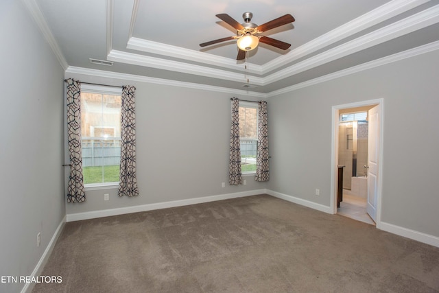 unfurnished bedroom featuring crown molding, baseboards, a tray ceiling, carpet floors, and ensuite bathroom