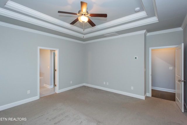 unfurnished bedroom with a tray ceiling, crown molding, baseboards, and carpet floors