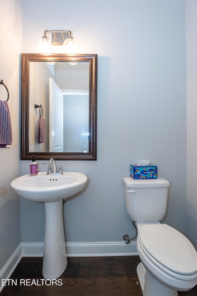 bathroom with toilet, wood finished floors, and baseboards