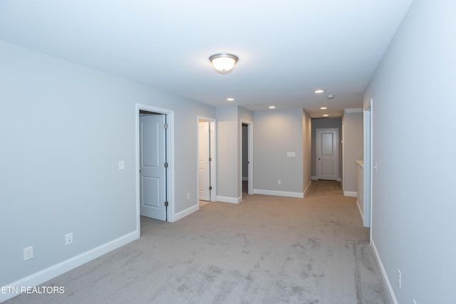 empty room featuring recessed lighting, light colored carpet, and baseboards