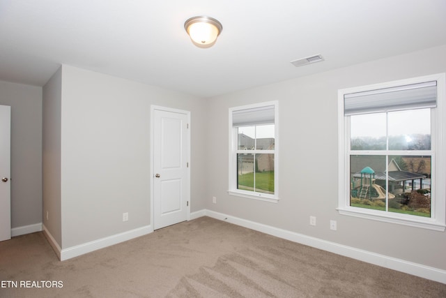 spare room featuring visible vents, baseboards, and light carpet