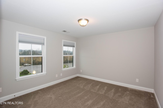 empty room with visible vents, baseboards, and dark carpet