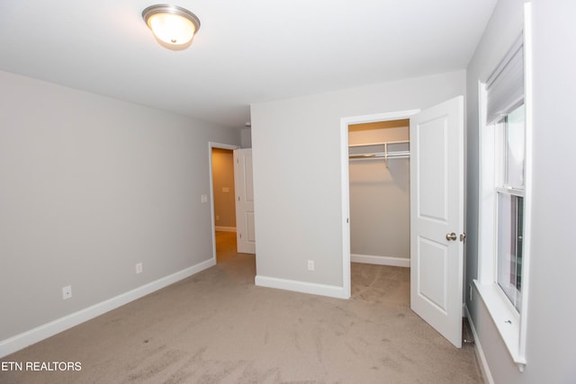 unfurnished bedroom featuring a spacious closet, carpet flooring, baseboards, and a closet