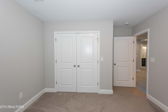 unfurnished bedroom featuring a closet, baseboards, and carpet