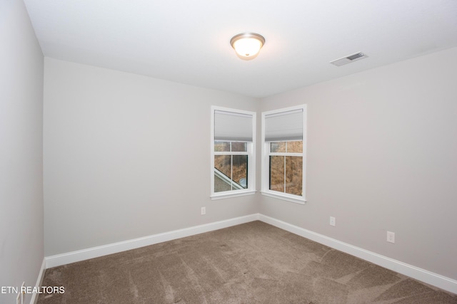 empty room featuring visible vents, carpet floors, and baseboards