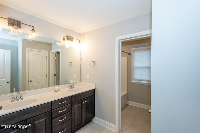 bathroom with double vanity, shower / bathing tub combination, baseboards, and a sink