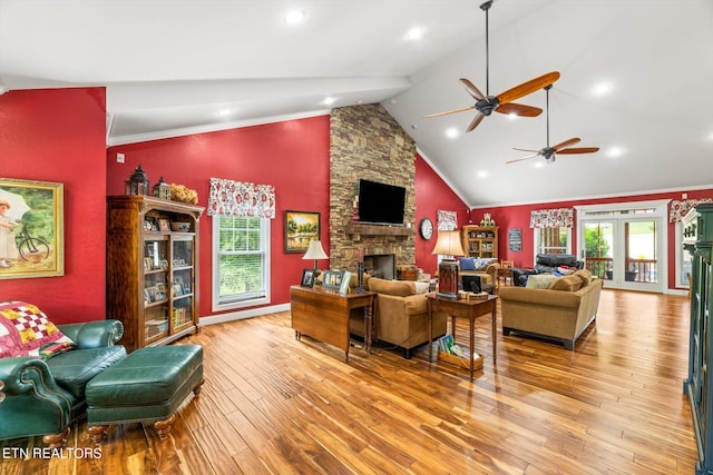 living room with ceiling fan, french doors, light hardwood / wood-style flooring, crown molding, and a fireplace