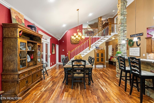 dining space featuring lofted ceiling, wood-type flooring, ornate columns, and ornamental molding