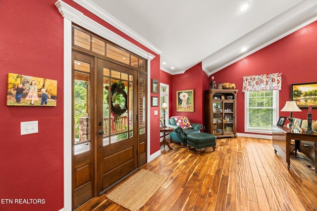 entryway featuring hardwood / wood-style flooring, lofted ceiling, and ornamental molding