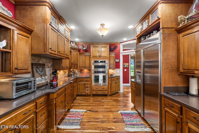 kitchen with tasteful backsplash, stainless steel appliances, and hardwood / wood-style flooring