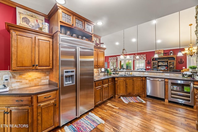 kitchen featuring kitchen peninsula, hanging light fixtures, beverage cooler, and appliances with stainless steel finishes