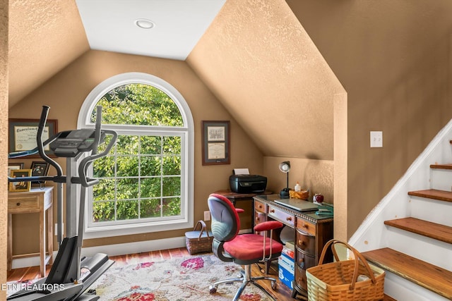 home office featuring lofted ceiling, a textured ceiling, and hardwood / wood-style flooring