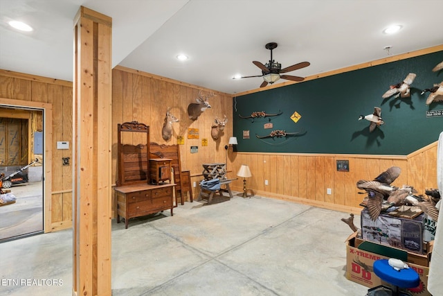 misc room with concrete flooring, ceiling fan, ornamental molding, and wood walls