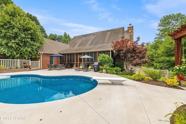 view of swimming pool featuring a patio area, a sunroom, and a diving board