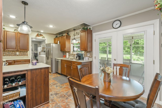 kitchen featuring backsplash, light tile patterned floors, ornamental molding, appliances with stainless steel finishes, and decorative light fixtures