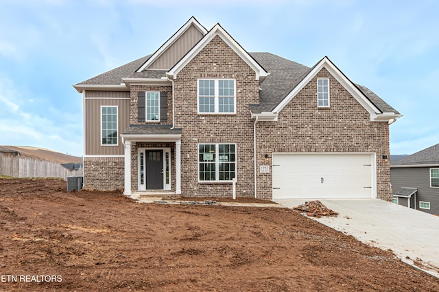 view of front of home with central AC unit, an attached garage, brick siding, driveway, and board and batten siding