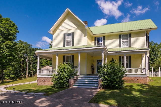 country-style home featuring a porch and a front lawn