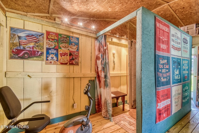 workout room featuring hardwood / wood-style floors, lofted ceiling, and wooden walls