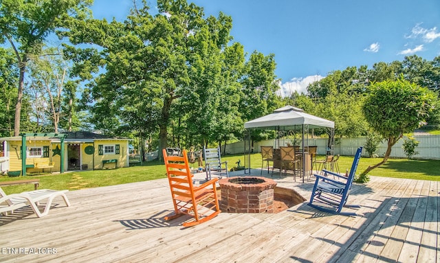 wooden deck with a lawn and an outdoor fire pit