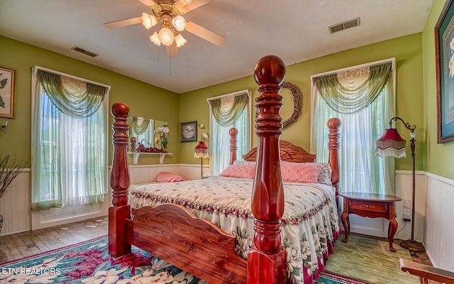 bedroom featuring multiple windows, hardwood / wood-style floors, and ceiling fan