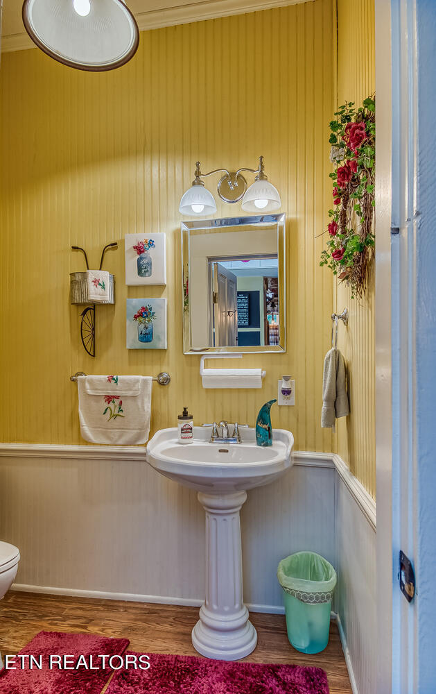 bathroom featuring hardwood / wood-style floors, sink, toilet, and crown molding