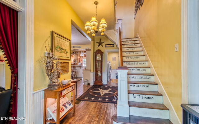 stairway with hardwood / wood-style floors and an inviting chandelier