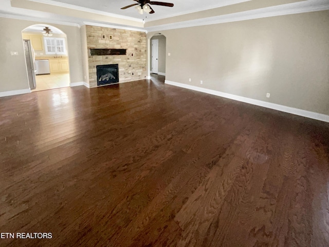 unfurnished living room featuring a tray ceiling, dark hardwood / wood-style floors, and ornamental molding