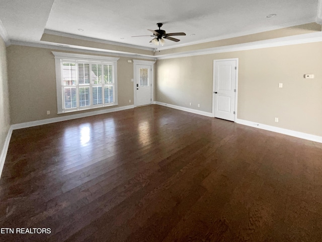 unfurnished room with ceiling fan, a raised ceiling, crown molding, and dark wood-type flooring