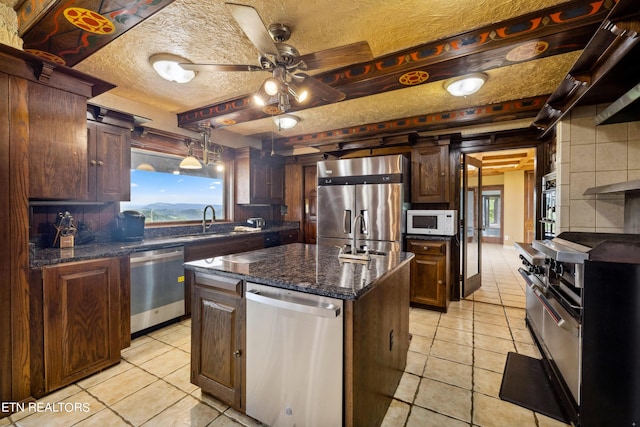 kitchen featuring a center island, sink, ceiling fan, a textured ceiling, and stainless steel appliances