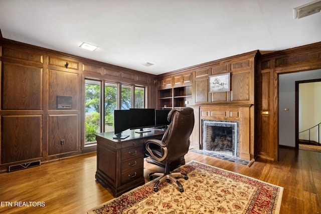 office space with built in shelves, wooden walls, and hardwood / wood-style floors