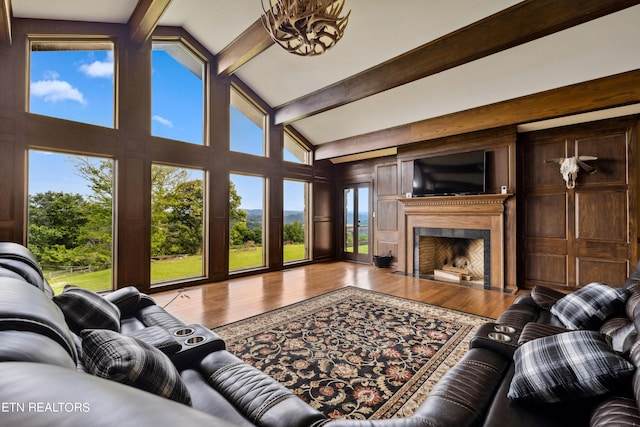 living room with vaulted ceiling with beams, plenty of natural light, a high end fireplace, and hardwood / wood-style floors