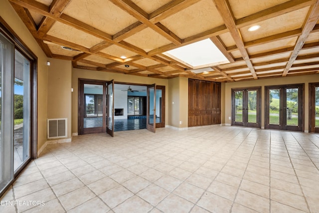 unfurnished living room with french doors, coffered ceiling, and beam ceiling