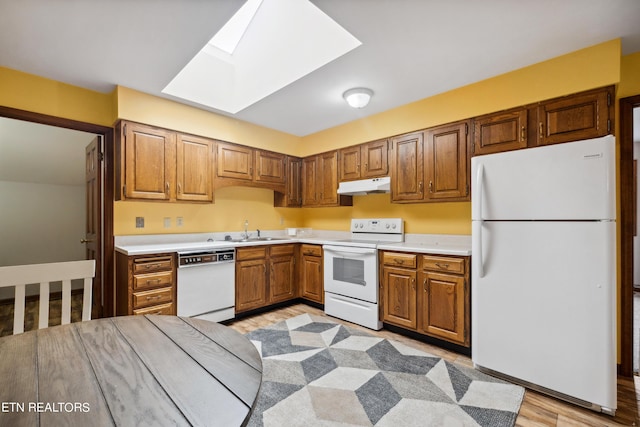 kitchen with light hardwood / wood-style floors, white appliances, sink, and a skylight