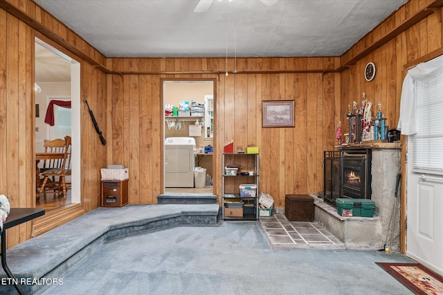 living room featuring carpet, washer / clothes dryer, and wood walls