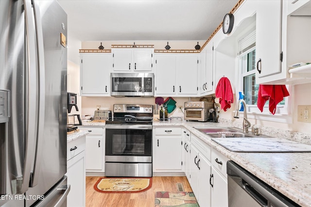 kitchen with white cabinets, light wood-type flooring, appliances with stainless steel finishes, and sink