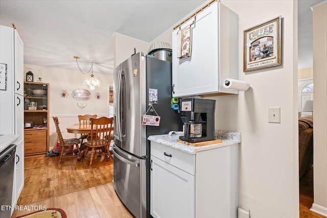 kitchen featuring white cabinetry, stainless steel appliances, light hardwood / wood-style flooring, and a notable chandelier