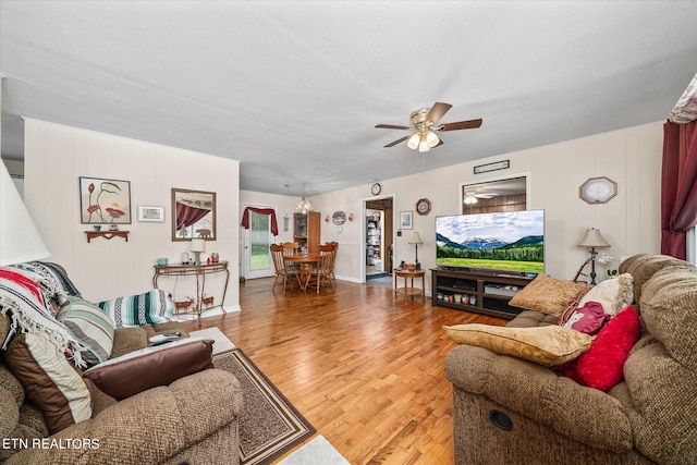 living room featuring ceiling fan with notable chandelier and hardwood / wood-style floors