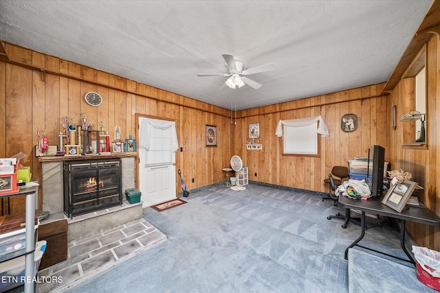 interior space with carpet floors, ceiling fan, wooden walls, and a textured ceiling