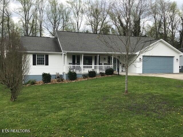 ranch-style house featuring a garage, a front yard, and covered porch