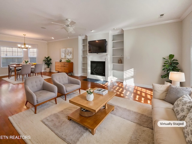 living room with crown molding, hardwood / wood-style flooring, and ceiling fan with notable chandelier