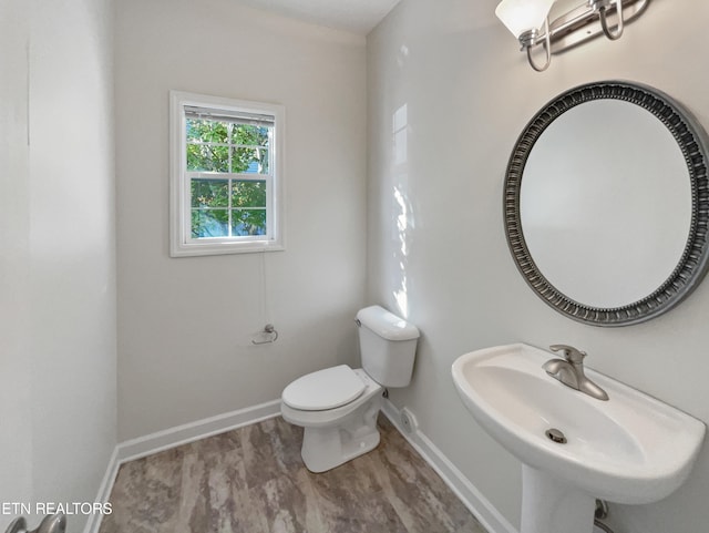 bathroom featuring toilet, sink, and wood-type flooring