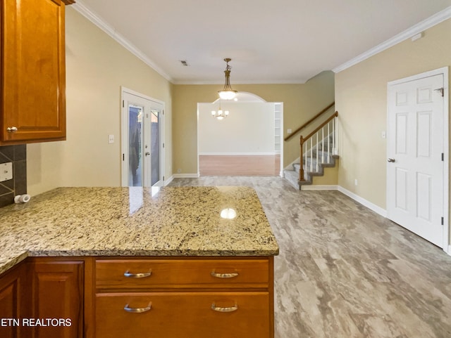 kitchen featuring light stone countertops, ornamental molding, pendant lighting, and an inviting chandelier