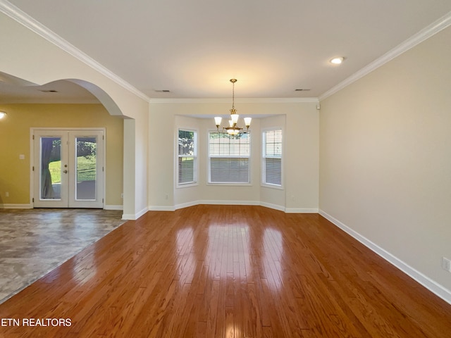 empty room featuring ornamental molding, hardwood / wood-style floors, a notable chandelier, and french doors