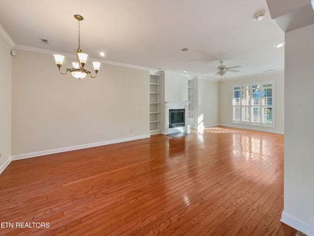 unfurnished living room with light hardwood / wood-style floors, ornamental molding, built in features, and ceiling fan with notable chandelier