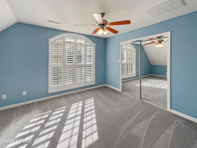 unfurnished bedroom featuring a closet, ceiling fan, vaulted ceiling, and carpet floors