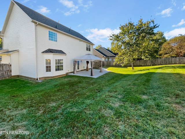 rear view of house featuring a gazebo, a patio area, and a lawn