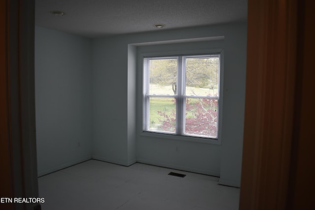 spare room with a healthy amount of sunlight, baseboards, and visible vents