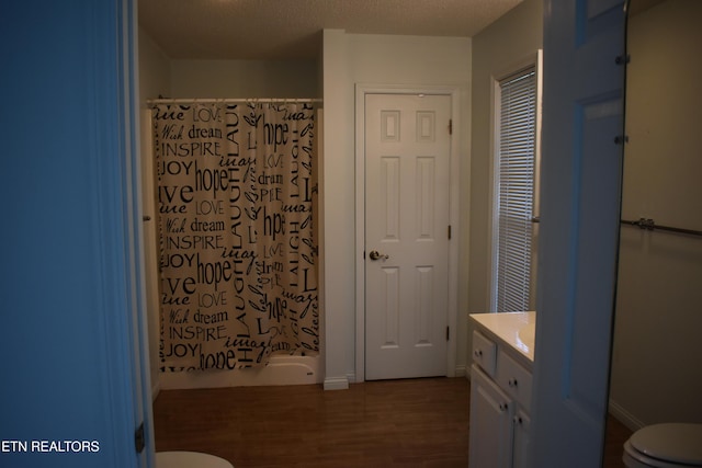 bathroom with toilet, curtained shower, wood finished floors, and vanity