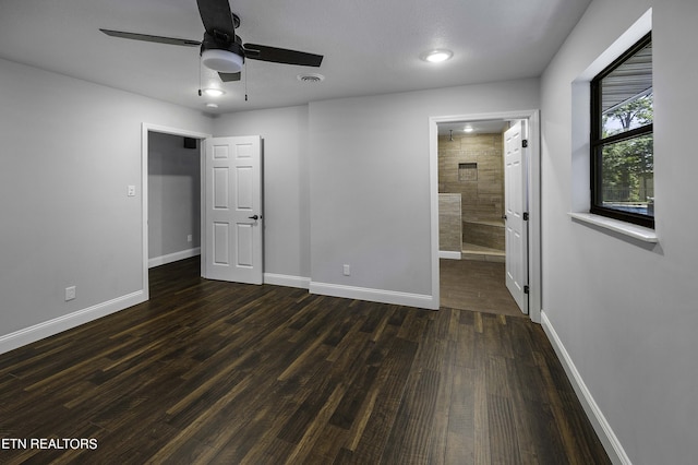 unfurnished bedroom featuring ensuite bath, ceiling fan, and dark wood-type flooring